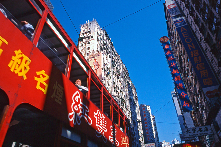 Looking up at man in a bright red double-decker bus, Hong Kong