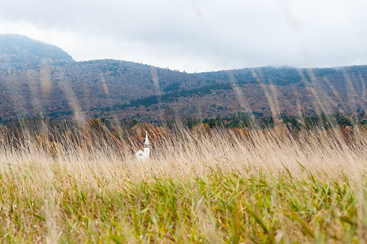 White steeple church seen through distant field, New Hampshire